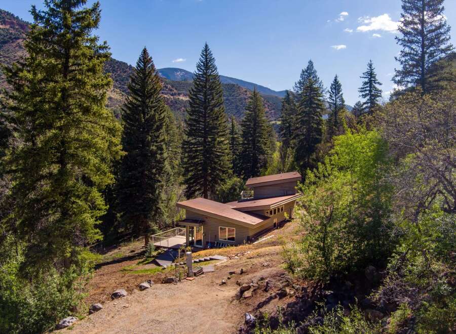 Nestled amidst a serene forest landscape, this modern home offers a unique architectural design with a distinctive multi-level roofline.