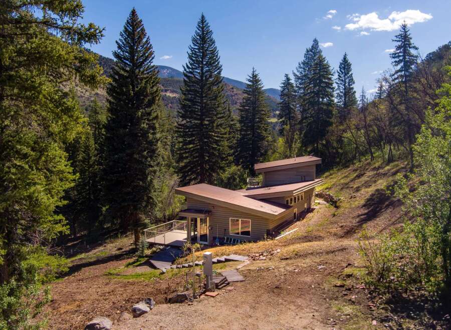 Nestled amidst a serene forest landscape, this modern home offers a unique architectural design with striking angled roofs and expansive windows.