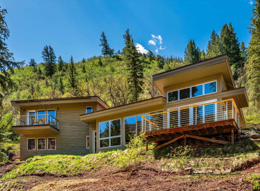 Experience modern living nestled in nature with this stunning home featuring expansive windows that bring the outdoors in.