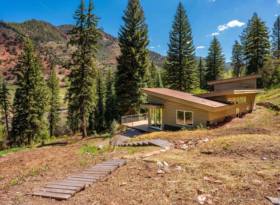 Nestled amidst a serene mountain landscape, this modern home offers a unique architectural design with a striking angled roof.