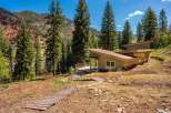 Nestled amidst a serene mountain landscape, this modern home offers a unique architectural design with a striking angled roof.