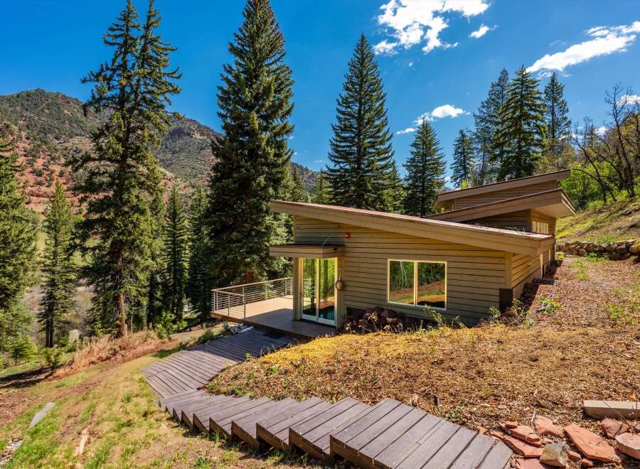 Nestled amidst towering pine trees and a scenic mountain backdrop, this modern home offers a unique architectural design.
