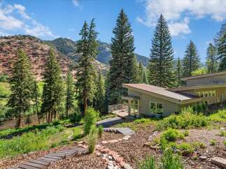 Nestled amidst towering pine trees and a serene river, this modern architectural gem offers a unique living experience.