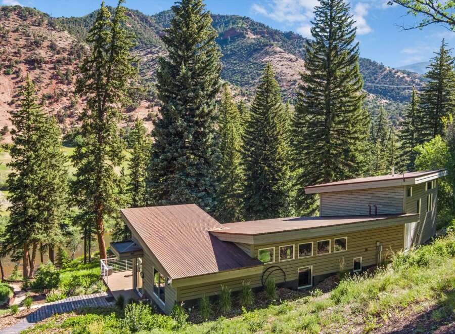 Nestled amidst towering evergreen trees and rolling hills, this modern home offers a serene retreat.