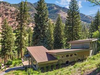 Nestled amidst towering evergreen trees and rolling hills, this modern home offers a serene retreat.