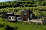 Experience modern luxury in this stunning hillside residence, featuring a striking dark wood facade and expansive glass windows that seamlessly blend indoor and outdoor living.