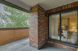 Enjoy the outdoors from this charming balcony, featuring a classic brick accent wall and a large sliding glass door that opens to a bright interior.