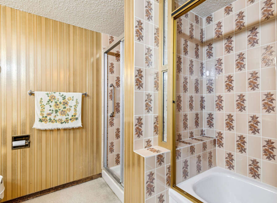 Step into a retro-inspired bathroom featuring a charming floral towel and a unique vertical striped wallpaper.