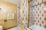 Step into a retro-inspired bathroom featuring a charming floral towel and a unique vertical striped wallpaper.