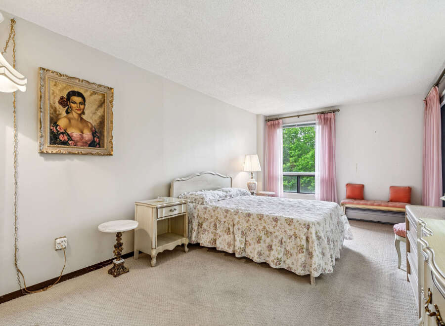 Step into this charming bedroom featuring a floral-patterned bedspread and a decorative portrait above the nightstand.