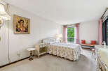 Step into this charming bedroom featuring a floral-patterned bedspread and a decorative portrait above the nightstand.