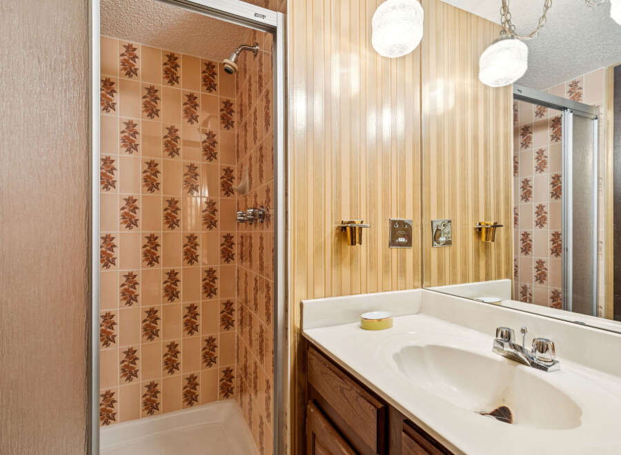 Step into this charming bathroom featuring a tiled shower with a glass door and a vanity with a large mirror.