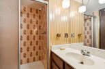 Step into this charming bathroom featuring a tiled shower with a glass door and a vanity with a large mirror.