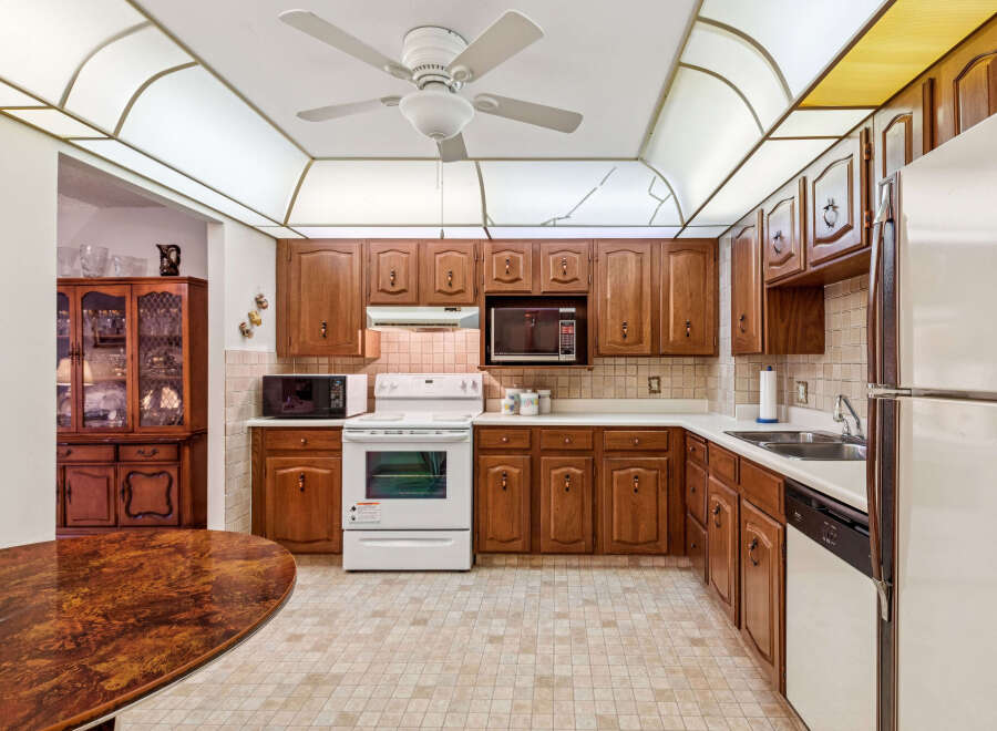 This charming kitchen features warm wood cabinetry, a white gas range, and a built-in microwave.