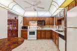 This charming kitchen features warm wood cabinetry, a white gas range, and a built-in microwave.