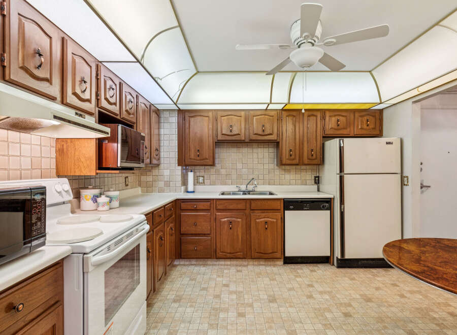 This charming kitchen features warm wooden cabinetry and a tiled backsplash, offering a classic and inviting atmosphere.