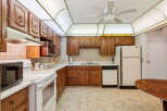 This charming kitchen features warm wooden cabinetry and a tiled backsplash, offering a classic and inviting atmosphere.
