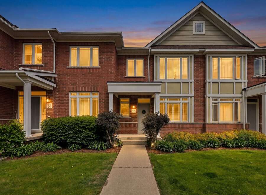 This stunning brick townhouse offers a welcoming entrance with a covered porch and well-maintained landscaping.