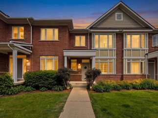 This stunning brick townhouse offers a welcoming entrance with a covered porch and well-maintained landscaping.
