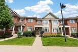 Discover this charming brick townhouse offering a welcoming facade with a well-maintained lawn and garden beds.
