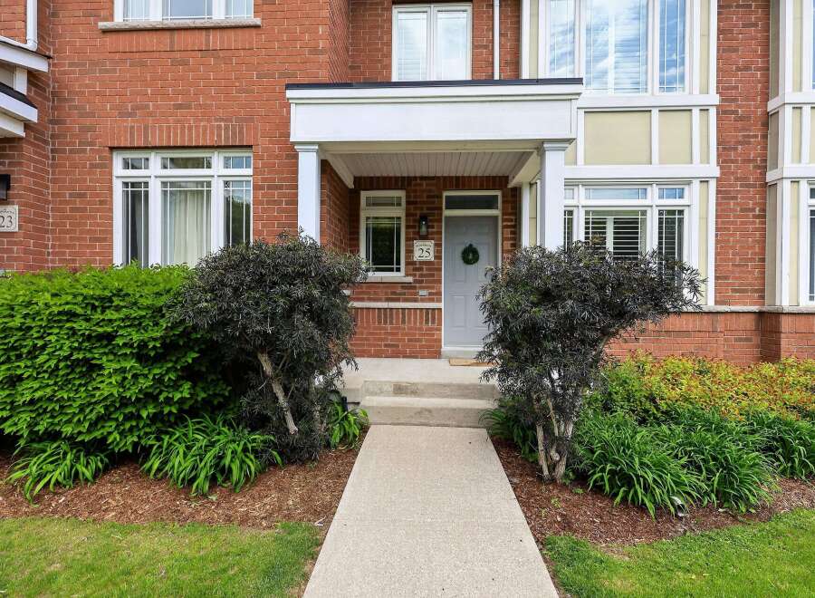 Welcome to this charming brick townhouse featuring a welcoming covered porch with a wreath-adorned front door.