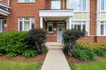 Welcome to this charming brick townhouse featuring a welcoming covered porch with a wreath-adorned front door.