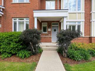 Welcome to this charming brick townhouse featuring a welcoming covered porch with a wreath-adorned front door.