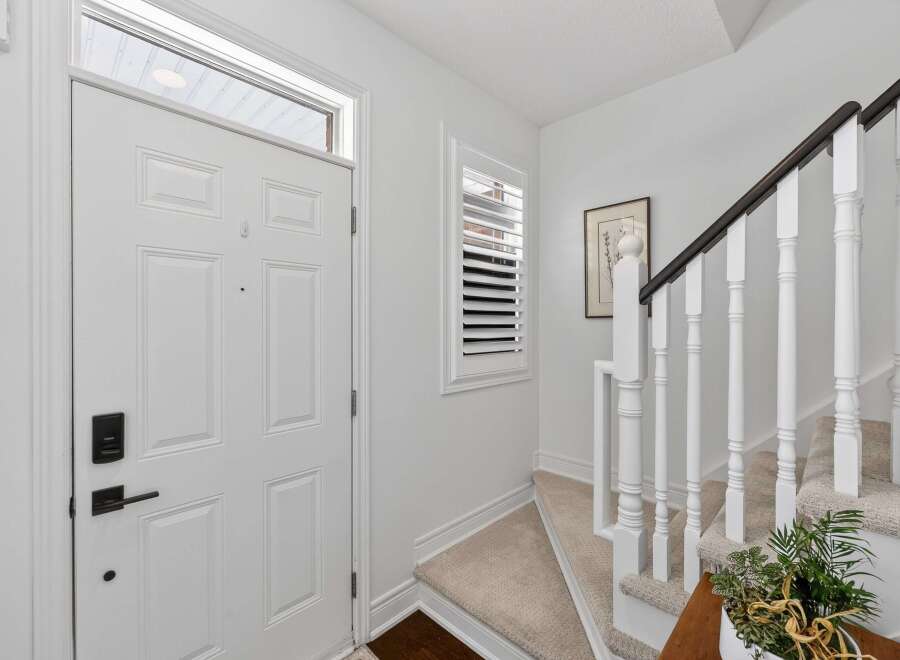Step into this welcoming entryway featuring a bright white front door with a modern black lockset.