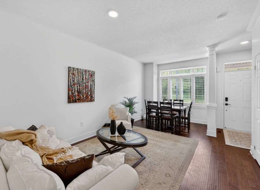Step into this inviting living and dining area, featuring a comfortable white sofa adorned with a cozy throw and decorative pillows.