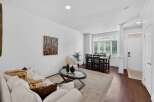 Step into this inviting living and dining area, featuring a comfortable white sofa adorned with a cozy throw and decorative pillows.