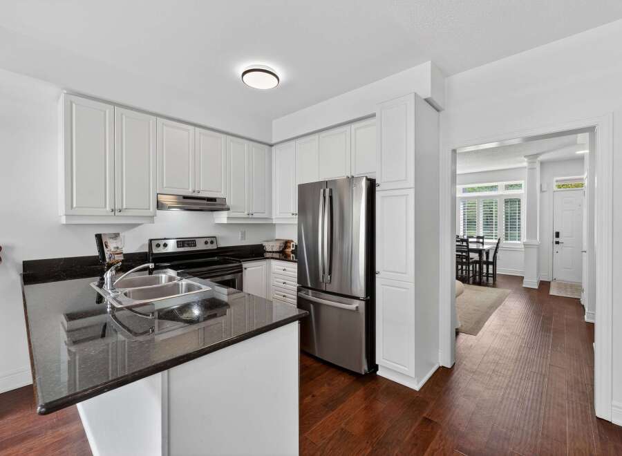 Step into this beautifully updated kitchen, featuring sleek white cabinetry and a modern granite countertop with a double sink.