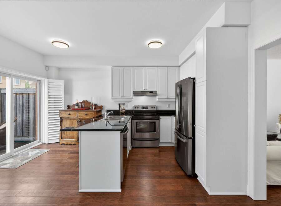 Discover this bright and airy kitchen featuring sleek white cabinetry and a spacious island with a granite countertop.