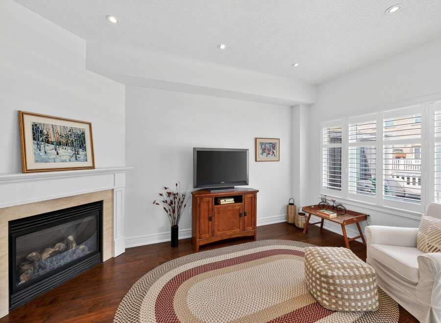 Cozy living room featuring a gas fireplace with a marble surround and a framed winter landscape painting.