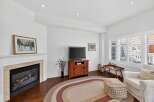 Cozy living room featuring a gas fireplace with a marble surround and a framed winter landscape painting.