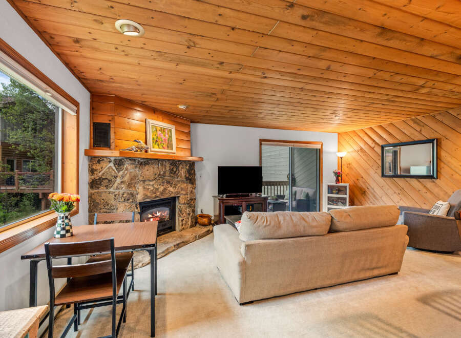 Cozy living room featuring a stone fireplace and warm wood paneling.