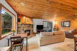 Cozy living room featuring a stone fireplace and warm wood paneling.