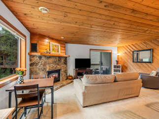 Cozy living room featuring a stone fireplace and warm wood paneling.
