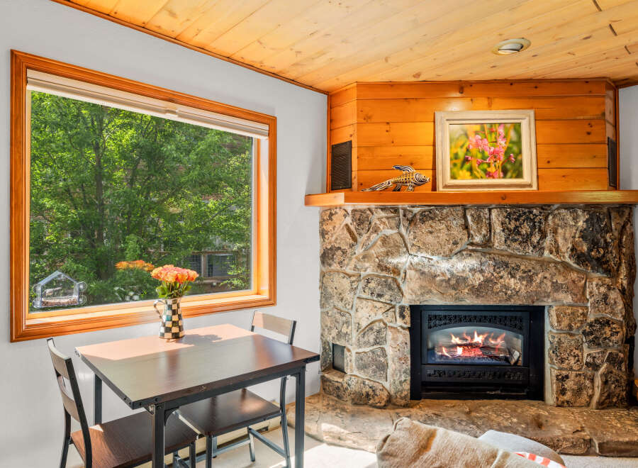 Cozy up by the stone fireplace in this charming living area, perfect for relaxing evenings.