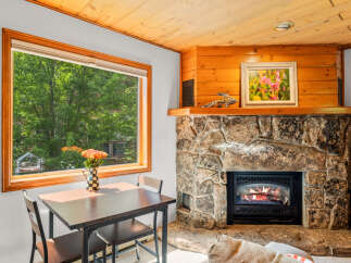 Cozy up by the stone fireplace in this charming living area, perfect for relaxing evenings.