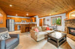 Cozy living room featuring a natural stone fireplace and a warm, wood-paneled ceiling.