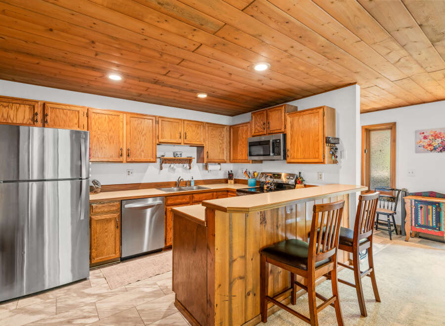This charming kitchen features warm wooden cabinetry and a coordinating wood-paneled breakfast bar, perfect for casual dining.