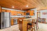 This charming kitchen features warm wooden cabinetry and a coordinating wood-paneled breakfast bar, perfect for casual dining.