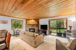 Cozy living room featuring a natural stone fireplace and a warm wood-paneled ceiling.