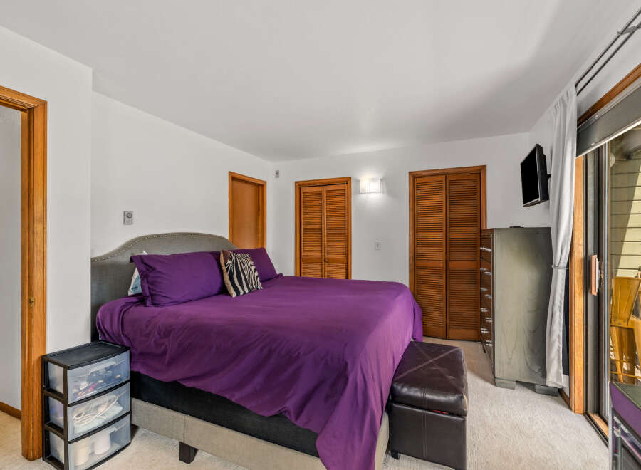 Discover comfort and style in this inviting bedroom, featuring a plush king-sized bed adorned with vibrant purple bedding and a chic upholstered headboard.