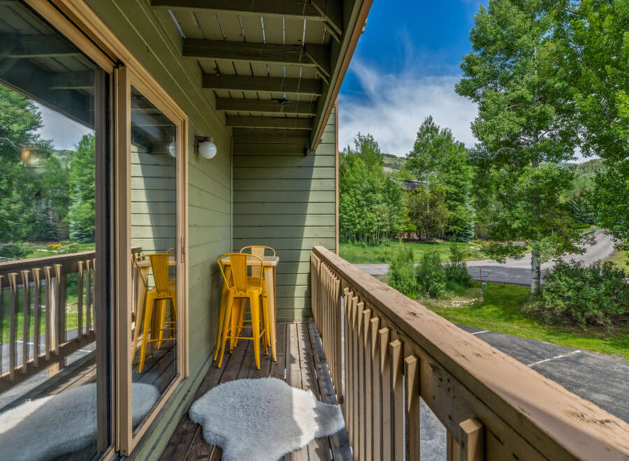 Enjoy your morning coffee or evening drink on this charming balcony, complete with a small table and two bright yellow stools.