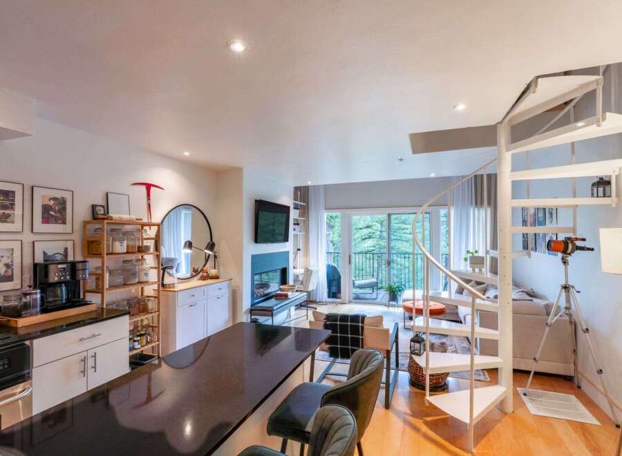 Discover modern living in this open-concept condo featuring a sleek kitchen with a breakfast bar and a cozy living area with a fireplace.