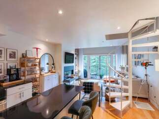 Discover modern living in this open-concept condo featuring a sleek kitchen with a breakfast bar and a cozy living area with a fireplace.