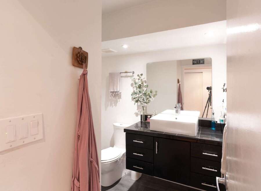 This modern bathroom features a sleek black vanity with a vessel sink and a large mirror, perfect for your morning routine.