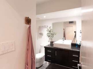 This modern bathroom features a sleek black vanity with a vessel sink and a large mirror, perfect for your morning routine.