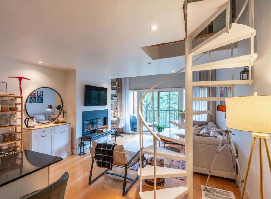 Experience modern living in this stunning multi-level apartment, featuring a striking spiral staircase that connects the open-concept living and dining areas.